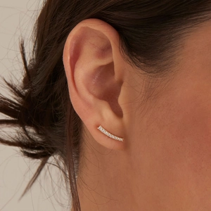 Close-up of gold curved ear crawler with sparkling diamonds worn on a model's ear