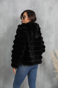 Detail of black faux fur jacket showing striped texture and hooded design on a model