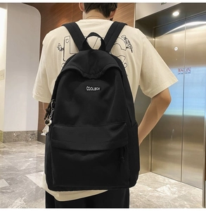 Rear view of a black minimalist backpack with COOLBOY text on a person in an elevator hall