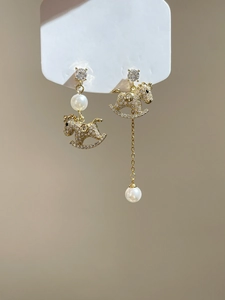 Detail of asymmetric gold-plated rocking horse earrings with pearls and crystals