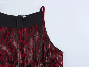 Gros plan sur la texture des paillettes rouges et noires et coutures de la robe de soirée