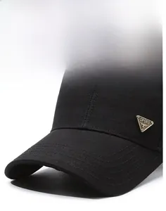 Detail of a black baseball cap featuring a bronze SPORT metal logo and textured fabric
