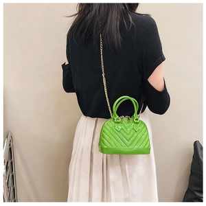 Back view of model wearing a bright green jelly shell bag with V-embossed pattern