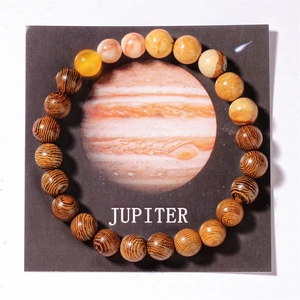 Detailed macro shot of solar system beads on a Jupiter card with tiger eye and wood