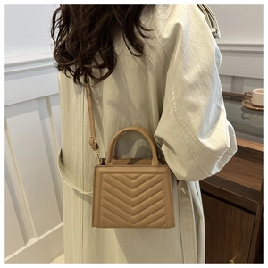 Model view of khaki quilted crossbody bag with stylish V-shaped stitching and top handle