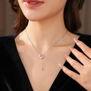 Gros plan d'un collier en argent avec pendentif cœur rose porté par un mannequin chic