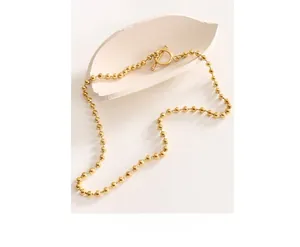 Detail of a golden beaded necklace with a classic T-bar toggle clasp on ceramic decor
