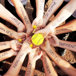 Macro detail of mini baseball bat keychain and yellow softball with teamwork graphics