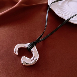 Detailed macro view of irregular silver mirror pendant on a black leather cord necklace
