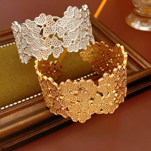 Macro detail of镂空 cutout floral cuff bracelets in gold and silver on vintage frame