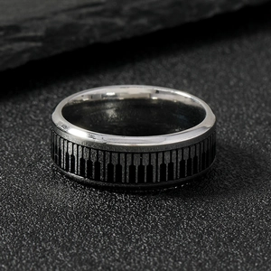 Minimalist stainless steel ring with black and white piano key pattern on stone surface