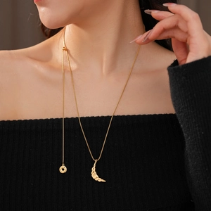 Detail of 18k gold plated croissant pendant necklace worn on a black knit shoulder