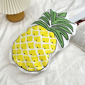 Detailed view of a pineapple shaped decorative pillow on a bed with a warm pleated lamp