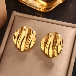 Close-up of golden irregular disc stud earrings with polished ripple texture surface