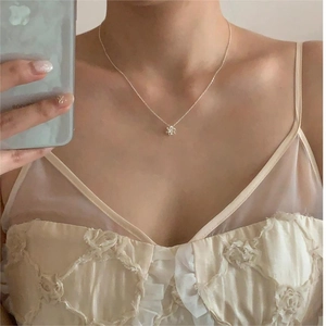 Wearing view of a minimalist 925 silver flower pendant necklace for women shown in a mirror