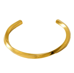 Macro shot of twisted gold C-shaped stainless steel bangle with geometric metal texture