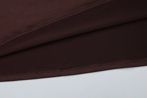 Gros plan sur l'ourlet à double aiguille d'une robe en maille marron foncé texturée