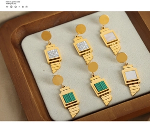 Detailed macro view of gold geometric earrings with pearl, malachite, and rhinestone inlays