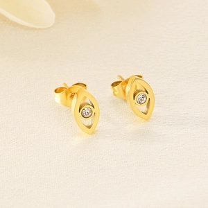 Makroaufnahme goldener Evil Eye Ohrstecker mit weißem Zirkon auf glänzendem Satinstoff