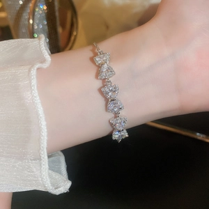 Detailed view of silver bow-knot bracelet with inlaid zircons worn on female wrist