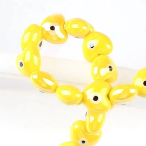 Handmade yellow ceramic heart beads featuring devil eye patterns for DIY jewelry making