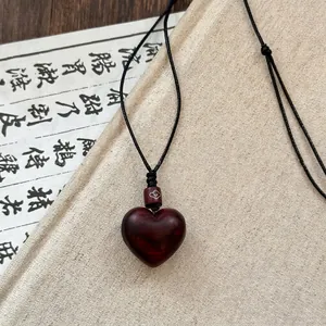 Macro detail of heart-shaped dark red wood pendant with silver cloud pattern bead