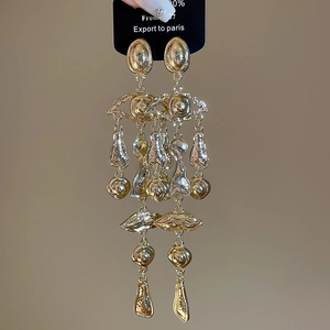 Detail of gold surrealist eye and lip tassel earrings with abstract metal elements