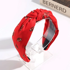 Close-up of red knotted headband with brown football patterns on display stand