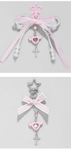 Detail of pink bow bag charms featuring faux pearls and heart pendants with silver crosses