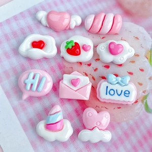 Flat lay of pink and white resin charms including heart, cloud, and strawberry shapes