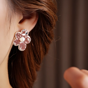 Detailed close-up of textured silver flower earrings with white pearls on a model