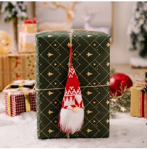 Detailed view of a red and white knitted Christmas gnome ornament on a gift box