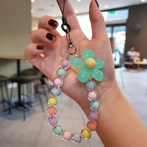 Close-up of macaron beaded phone charm with large green flower pendant and colorful beads