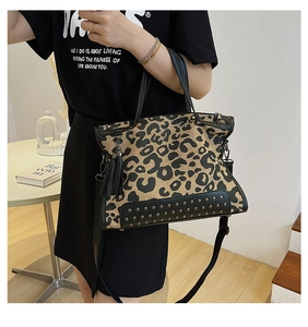 Close-up of stylish leopard print handbag with black leather straps and rivet detail