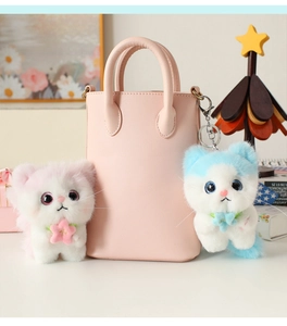 Detail of cute plush angel cat keychains in pink and blue on a stylish handbag