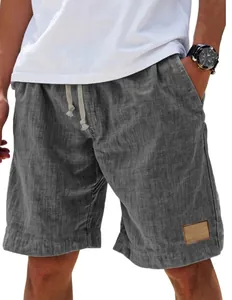 Close-up of men's linen shorts showing elastic waistband, beige drawstring, and brown leather tag
