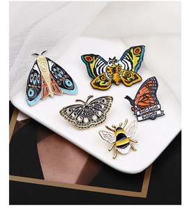 Macro shot of colorful enamel insect brooches featuring moths, bees and butterfly pins