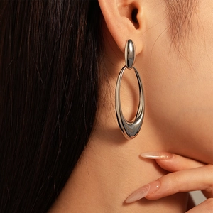 Macro view of silver vintage hollow oval geometric earrings on model's ear