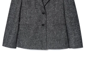 Dettaglio macro del blazer in tweed spina di pesce grigio con bottoni neri e texture