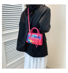 Pink crossbody bag with colorful block patterns worn on a minimalist black outfit