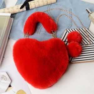 Detail of red heart-shaped faux fur plush bag with gold chain and furry ball charms
