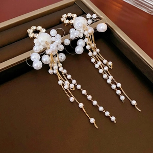 Detail of flower stud earrings with elegant pearl tassels and gold-tone finish chains