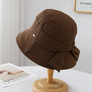 Cappello a secchiello marrone con fiocco e trama a scacchi su supporto in legno