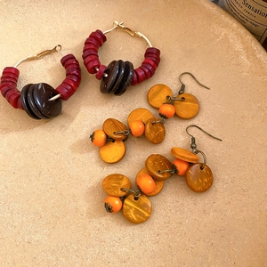 Détail de boucles d'oreilles ethniques avec perles en bois et breloques en noix de coco