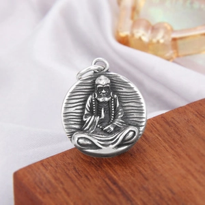 Détail macro du pendentif en argent s925 avec relief Bodhidharma sur fond en bois