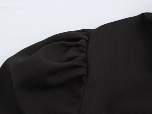 Close-up of elegant pleated puff sleeve detail on black French style dress