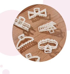 Close-up of elegant French pearl hair claw clips with bow and heart designs on wood