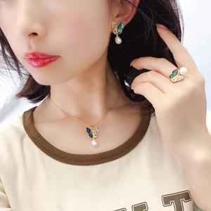 Detailed close-up of golden butterfly jewelry set with freshwater pearls and blue enamel