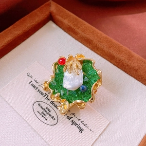 Detailed macro view of vintage baroque pearl brooch with green crystals in jewelry box