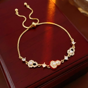 Detail of gold-plated gourd bracelet with pearls and red heart on wooden box